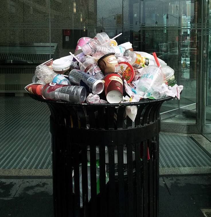 Cubo de basura peatonal con una montaña de basura
