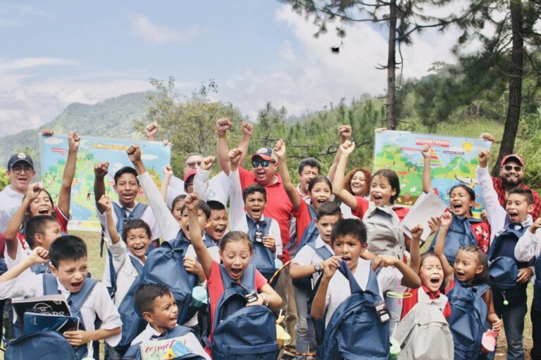 Grupo de niños sonriendo mientras cargan mochilas