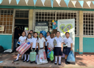 niños posando frente a banners de recacel y proyecto reconecta - en reciclatón escolar